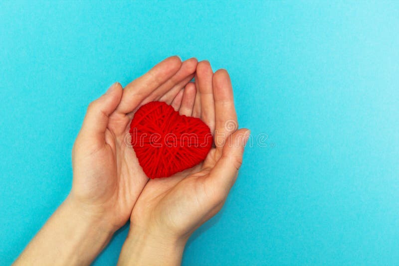 Coração vermelho nas mãos em um fundo azul imagem de stock royalty free Coração vermelho nas mãos em um fundo azul imagem de stock royalty free