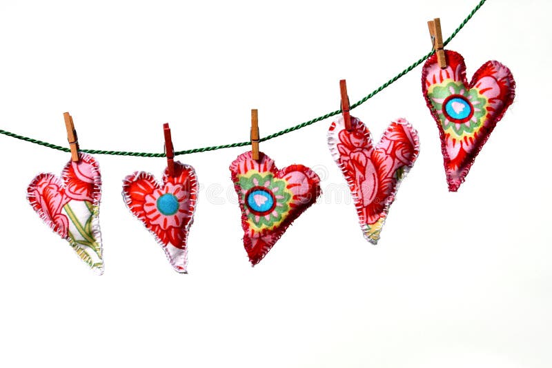 Red patterned textile love hearts hanging from washing line, isolated on white background. Red patterned textile love hearts hanging from washing line, isolated on white background.