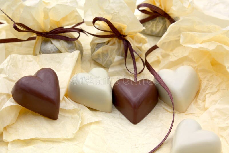 A closeup view of fancy white and dark chocolate hearts in a decorative display. A closeup view of fancy white and dark chocolate hearts in a decorative display.