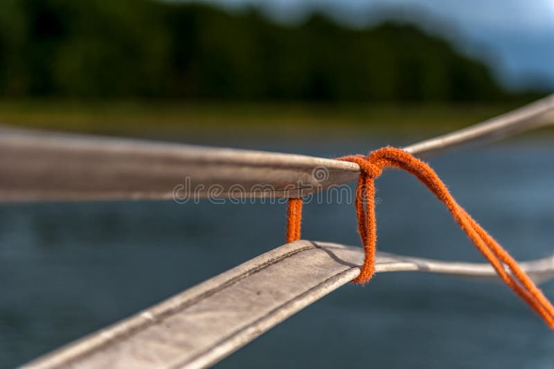 Corda arancio sottile legata sul legame delle cinghie fotografie stock Corda arancio sottile legata sul legame delle cinghie fotografie stock