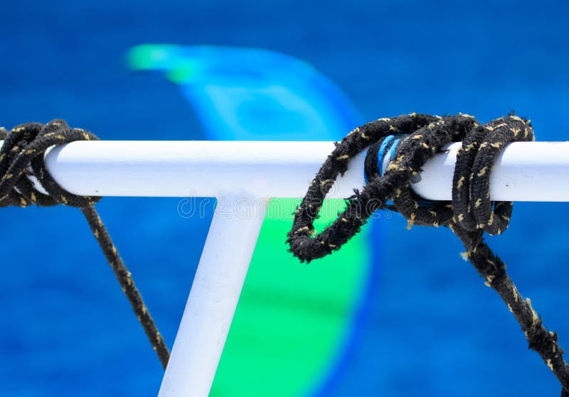 Corde di navigazione nere che attraversano nei nodi del legame intorno al tubo bianco della barca sul fondo blu profondo vago del fotografie stock libere da diritti Corde di navigazione nere che attraversano nei nodi del legame intorno al tubo bianco della barca sul fondo blu profondo vago del fotografie stock libere da diritti
