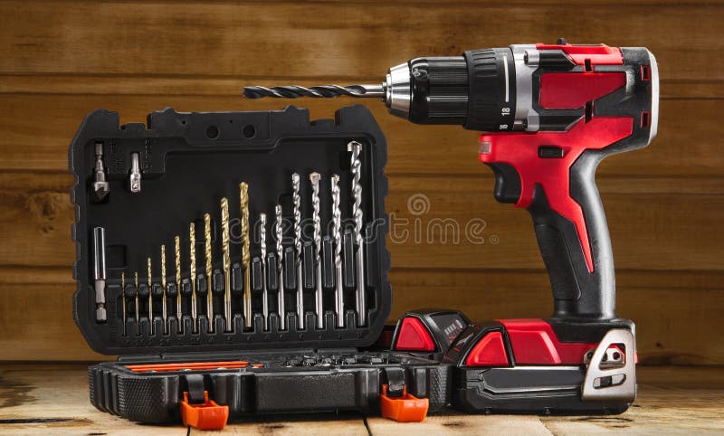 Cordless drill driver in red with rubberized handle in profile with drill bits set