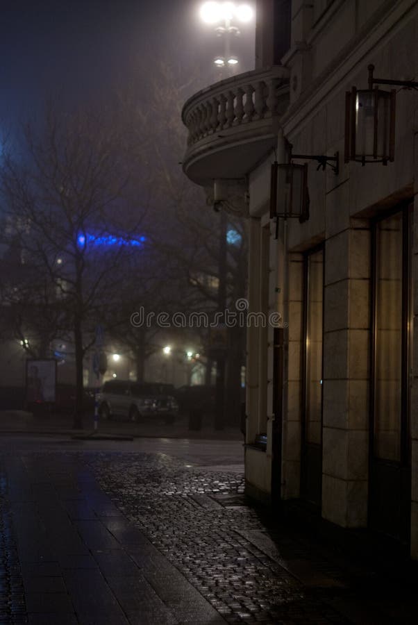The corner of a building in the city at night. It was a thick fog over the city this night, creating a lot of mood and shadows and a magical glow from the lights royalty free stock photo The corner of a building in the city at night. It was a thick fog over the city this night, creating a lot of mood and shadows and a magical glow from the lights royalty free stock photo