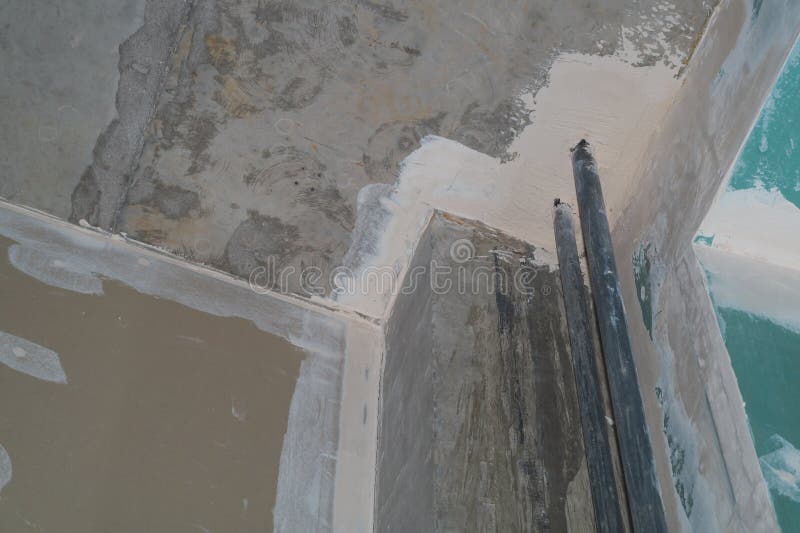 Corner between Concrete Wall and Drywall. Water Pipes in the Middle