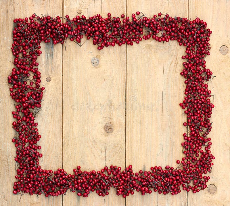 Cornice d'autunno di frutti rossi di un albero di spine su fondo di legno grezzo