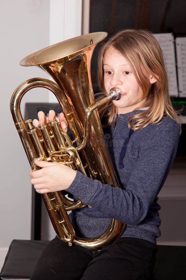 Young girl blowing on a baritone horn. Young girl blowing on a baritone horn.