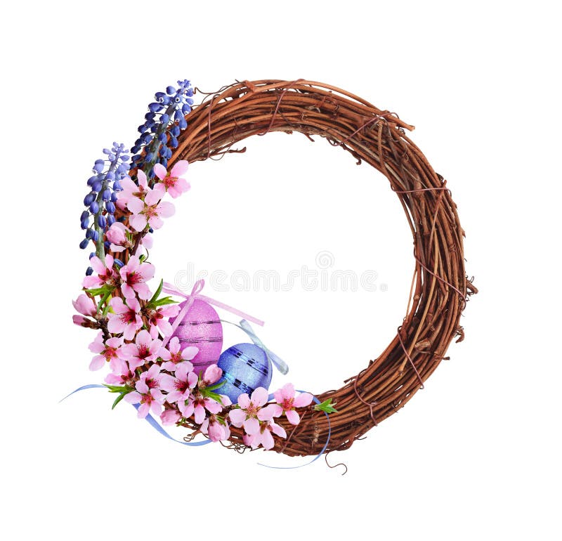 Corona di rattano marrone secco con fiori rosa e blu di primavera uova di Pasqua e nastro di satina isolati su bianco fotografia stock libera da diritti
