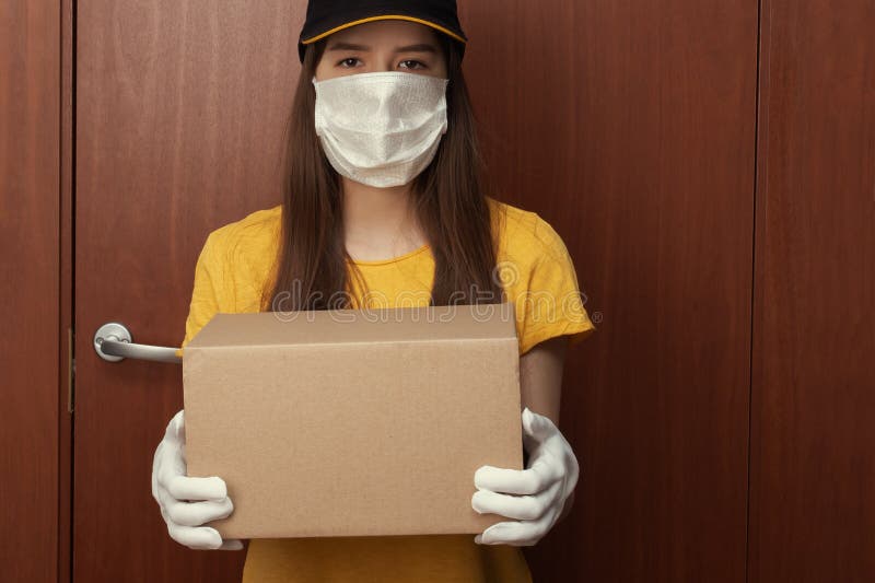 Coronavirus-bescherming Veilige levering van bestellingen via online winkels Jonge vrouwelijke koerier in uniform in een medisch stock afbeeldingen Coronavirus-bescherming Veilige levering van bestellingen via online winkels Jonge vrouwelijke koerier in uniform in een medisch stock afbeeldingen