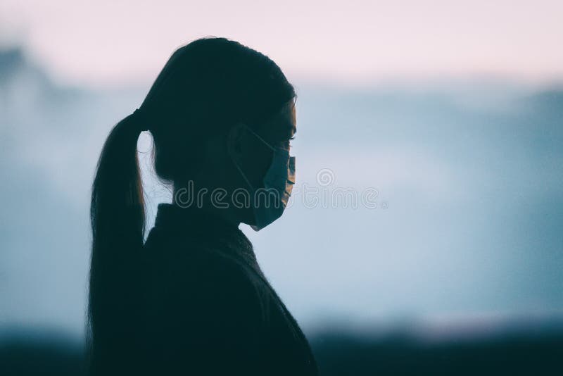 Coronavirus COVID-19 anxiety mental health problem sad woman wearing protective medical face mask silhouette alone
