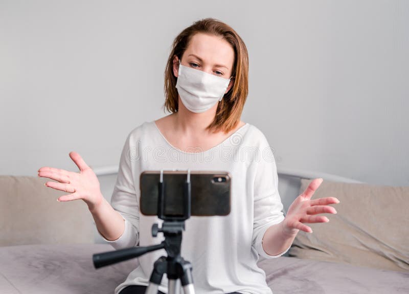 Coronavirus Mujer en cuarentena por disfrazar con máscara protectora, trabaja desde casa y usa teléfono móvil en el sofá Pandemia fotografía de archivo libre de regalías Coronavirus Mujer en cuarentena por disfrazar con máscara protectora, trabaja desde casa y usa teléfono móvil en el sofá Pandemia fotografía de archivo libre de regalías