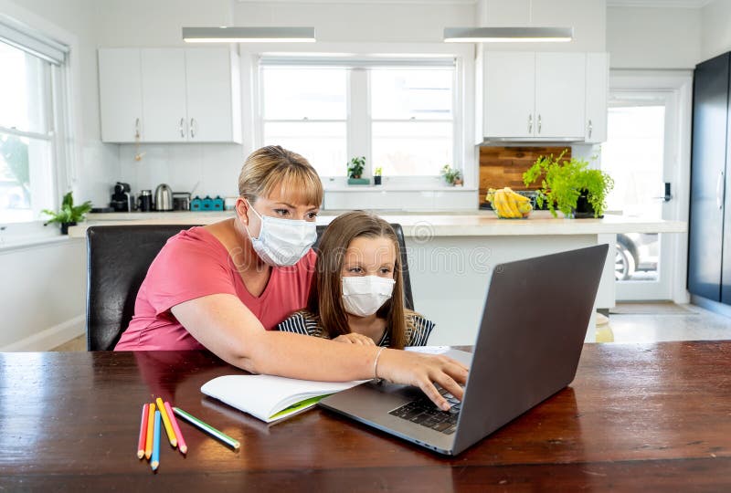 Coronavirus school closures and lockdown. Mum and bored daughter with masks studying online at home