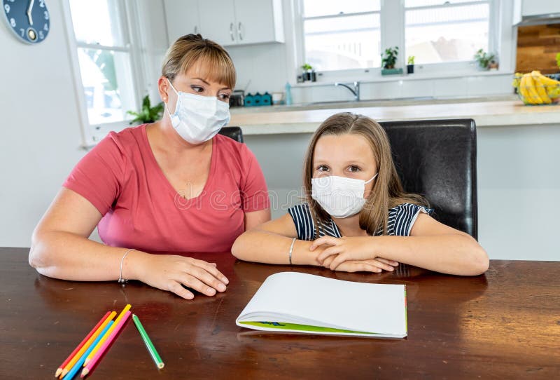Coronavirus school closures and lockdown. Mum and bored daughter with masks studying online at home stock photography Coronavirus school closures and lockdown. Mum and bored daughter with masks studying online at home stock photography