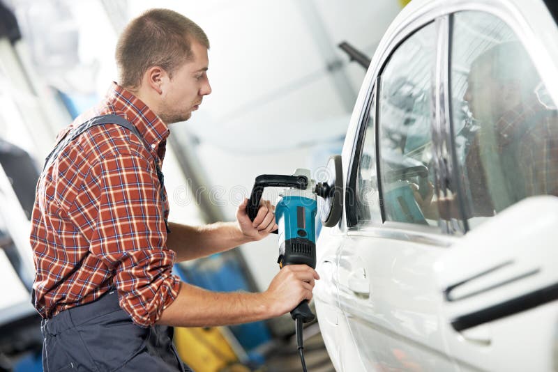Auto mechanic worker polishing car body at automobile repair and renew service station shop by power buffer machine. Auto mechanic worker polishing car body at automobile repair and renew service station shop by power buffer machine