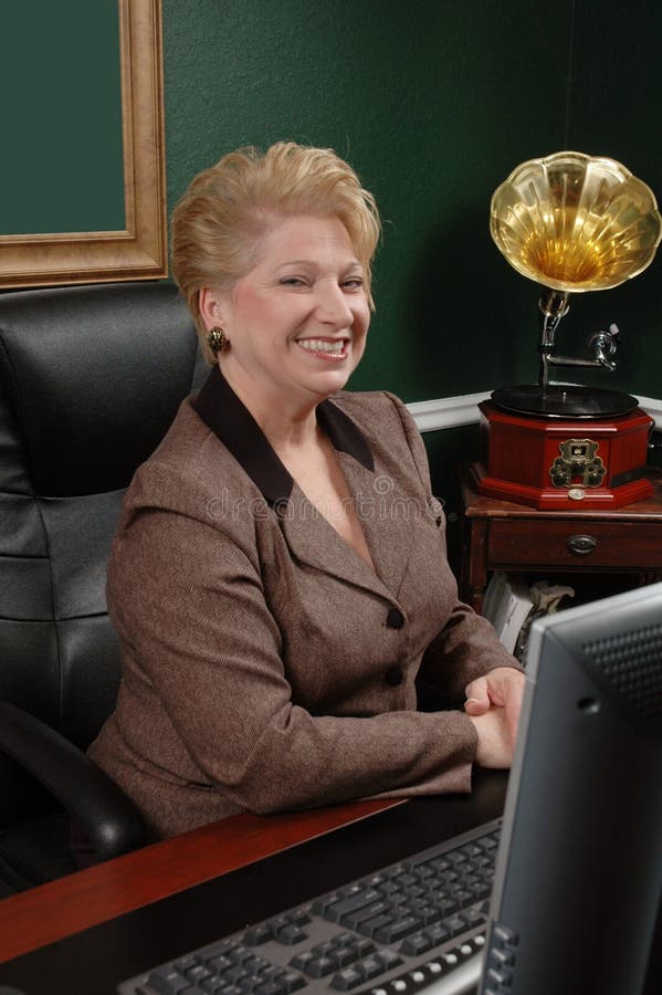 Business woman poses at her desk. Happy smiling woman. Business woman poses at her desk. Happy smiling woman.