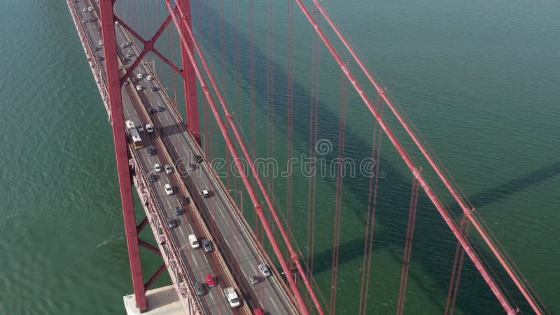 Corredera aérea vista frontal de denso tráfico de vehículos múltiples a través de la famosa gran suspensión roja ponte 25 de abril almacen de video