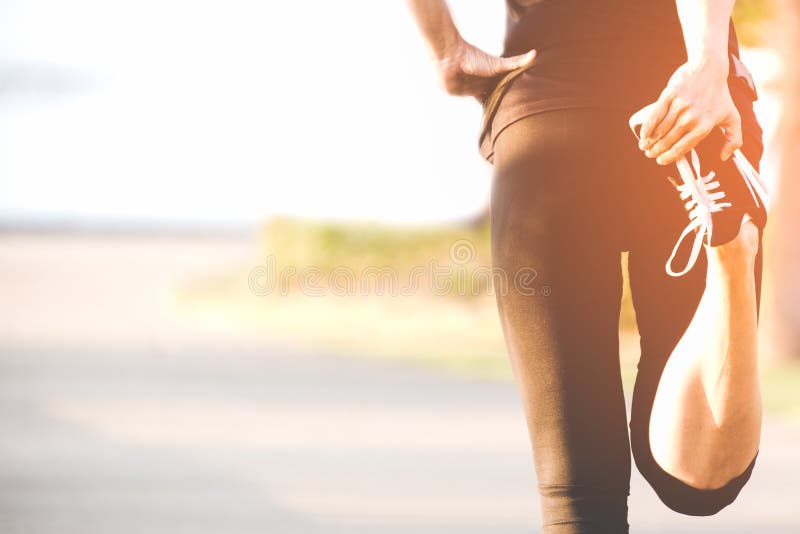 Corredor asiático de la mujer de la aptitud que estira las piernas antes de entrenamiento al aire libre del funcionamiento en el imagenes de archivo