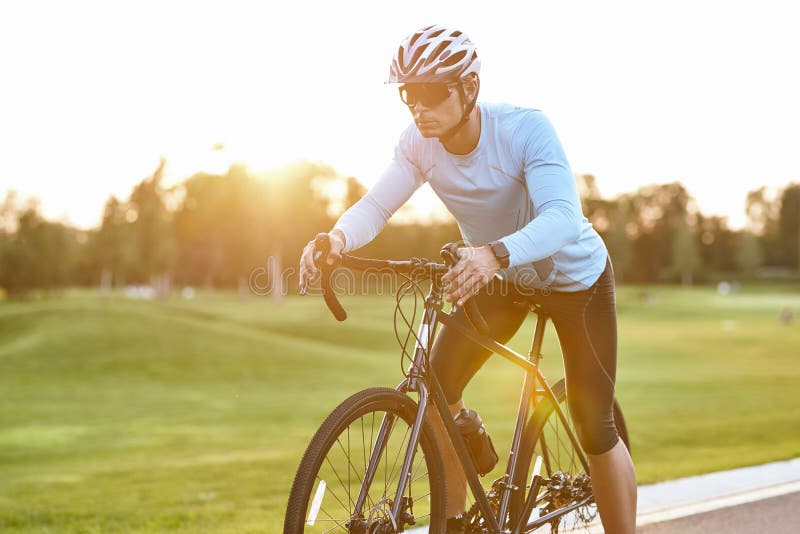 Corredor De Bicicletas De Carretera Profesional En Ropa Deportiva Y Casco  Protector Parado En La Carretera Al Atardecer Listo Para Imagen de archivo  - Imagen de asfalto, ruta: 198151301