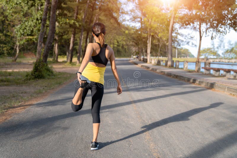 Corredor joven de la mujer de la aptitud que estira las piernas antes de funcionamiento en la ciudad, mujer joven del deporte de imagenes de archivo