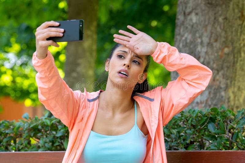 Corredor latin bonito que olha o ajuste e o selfie de tomada cansado e esgotado saudável em um parque verde moderno imagem de stock Corredor latin bonito que olha o ajuste e o selfie de tomada cansado e esgotado saudável em um parque verde moderno imagem de stock
