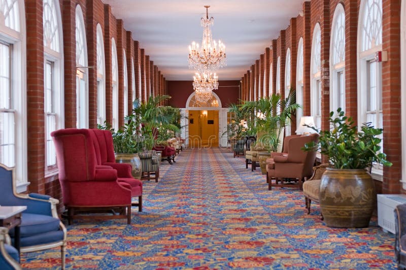 A luxurious, well decorated, elegant hallway with comfortable chairs, potted plants and chandeliers. A luxurious, well decorated, elegant hallway with comfortable chairs, potted plants and chandeliers.