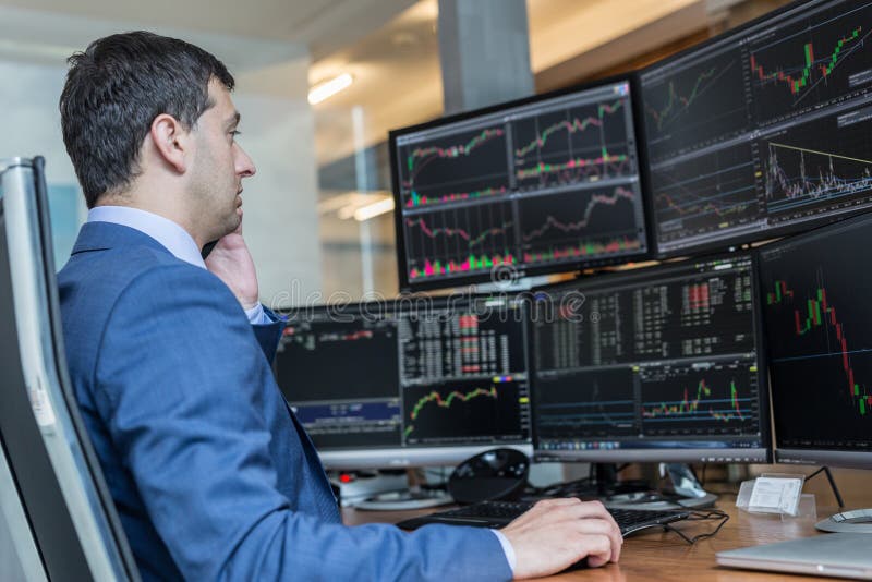 Male stock broker trading online watching charts and data analyses on multiple computer screens. Male stock broker trading online watching charts and data analyses on multiple computer screens.