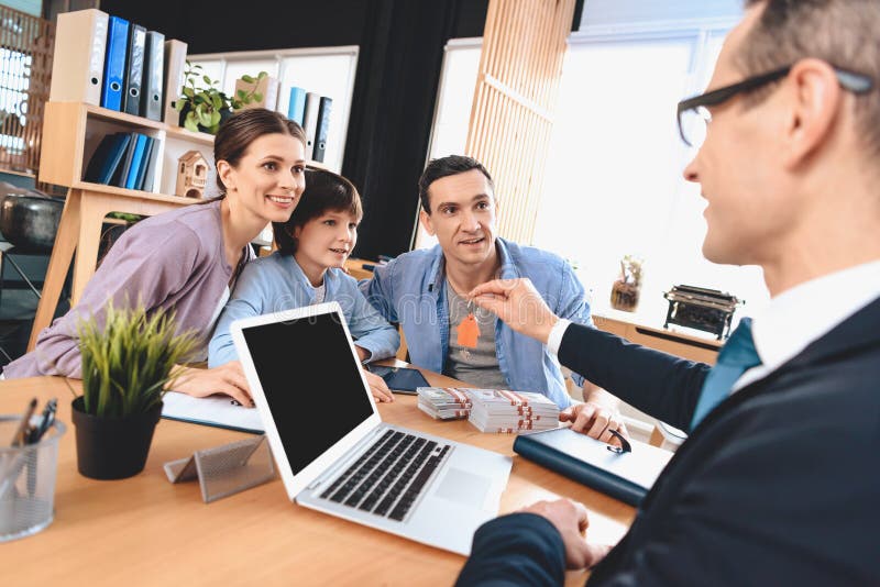 Corretor de imóveis que senta-se na mesa no escritório O corretor de imóveis está apresentando chaves para o apartamento novo à f foto de stock royalty free Corretor de imóveis que senta-se na mesa no escritório O corretor de imóveis está apresentando chaves para o apartamento novo à f foto de stock royalty free