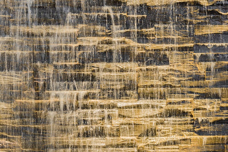 Corriente del agua que cae contra textura áspera de la cantería imagen de archivo libre de regalías Corriente del agua que cae contra textura áspera de la cantería imagen de archivo libre de regalías