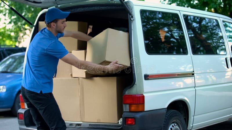 Corriere maschio che prende le scatole di consegna fuori dal furgone, società commovente, spedizione delle merci