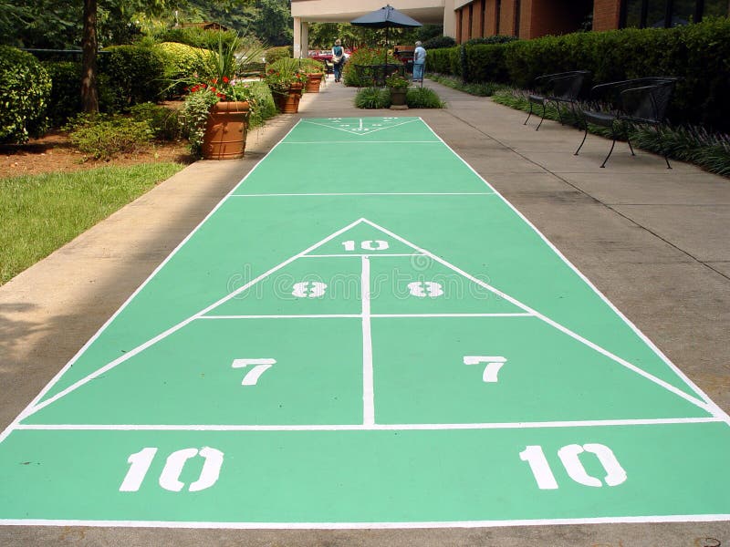 A game in which standing players shove or push wooden or plastic disks with a long cue toward numbered scoring sections marked on a floor or deck. A game in which standing players shove or push wooden or plastic disks with a long cue toward numbered scoring sections marked on a floor or deck.