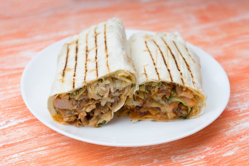 Corte en el medio rollo fresco de Shawarma del bocadillo con el lavash, pollo asado a la parrilla, setas, salsa, pepinos, col imágenes de archivo libres de regalías Corte en el medio rollo fresco de Shawarma del bocadillo con el lavash, pollo asado a la parrilla, setas, salsa, pepinos, col imágenes de archivo libres de regalías