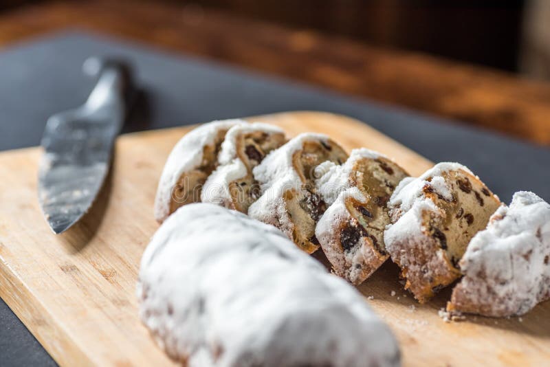 Corte Mini Marzipan Stollen del primer con el cuchillo en el tablero de madera
