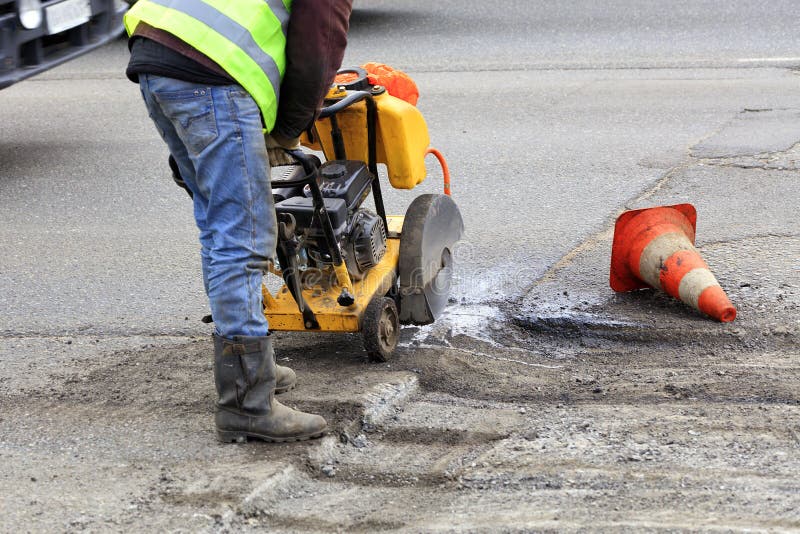 Cortes del trabajador al pedazo de m?n asfalto con un cortador de la gasolina durante la construcci?n de carreteras fotos de archivo libres de regalías Cortes del trabajador al pedazo de m?n asfalto con un cortador de la gasolina durante la construcci?n de carreteras fotos de archivo libres de regalías