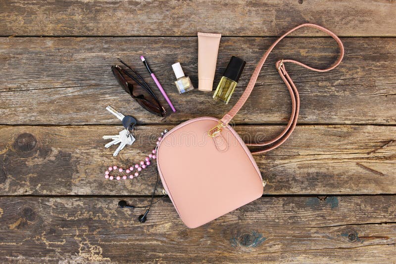 Cose dalla borsa aperta di signora I cosmetici e gli accessori delle donne sono caduto dalla borsa su vecchio fondo di legno fotografia stock libera da diritti Cose dalla borsa aperta di signora I cosmetici e gli accessori delle donne sono caduto dalla borsa su vecchio fondo di legno fotografia stock libera da diritti