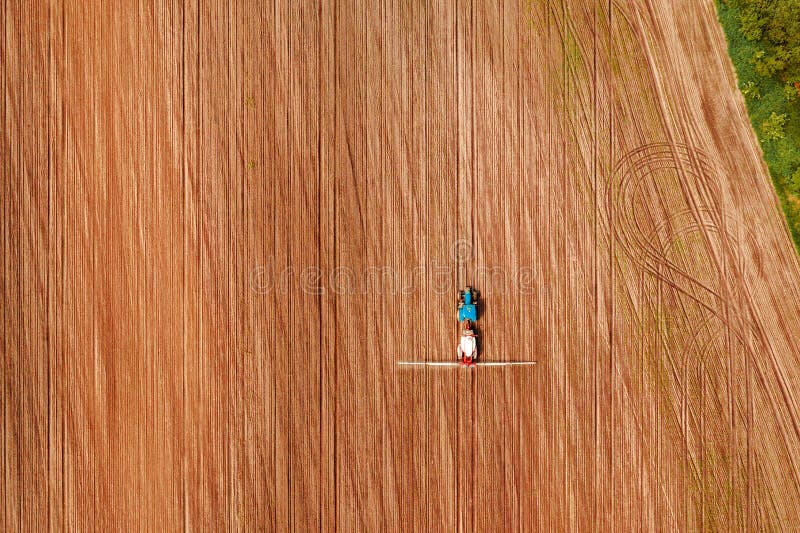Cosechas de rociadura del tractor en el campo, visión aérea foto de archivo Cosechas de rociadura del tractor en el campo, visión aérea foto de archivo