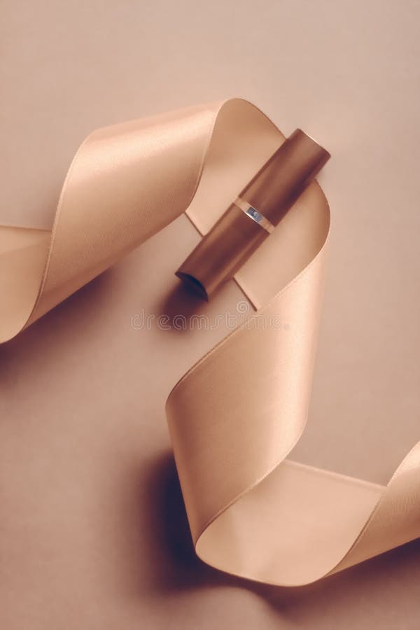 Luxury lipstick and silk ribbon on beige holiday background, make-up and cosmetics flatlay for beauty brand product design stock photography Luxury lipstick and silk ribbon on beige holiday background, make-up and cosmetics flatlay for beauty brand product design stock photography