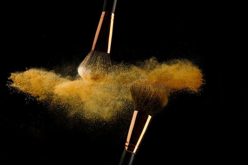 Cosmetic brush with golden powder spreading on black background