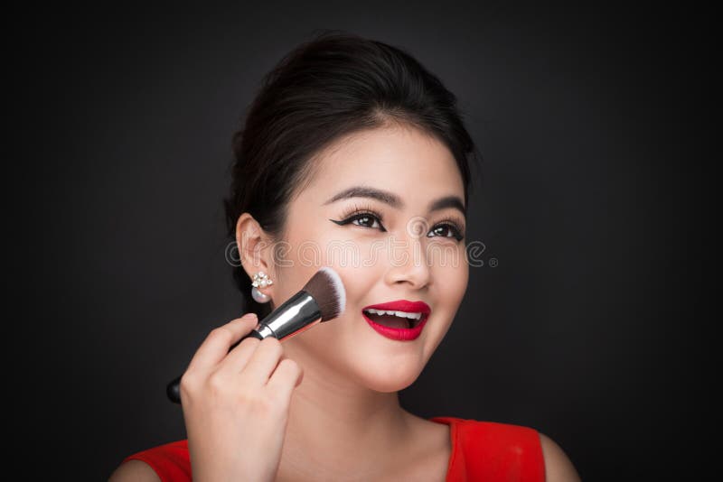 Cosmetic powder brush. Asian woman applying blusher on her cheek