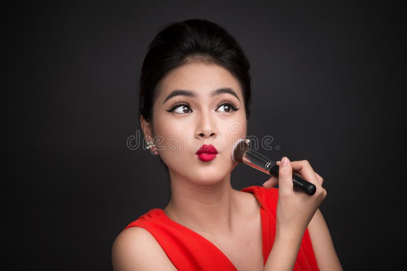 Cosmetic powder brush. Asian woman applying blusher on her cheek