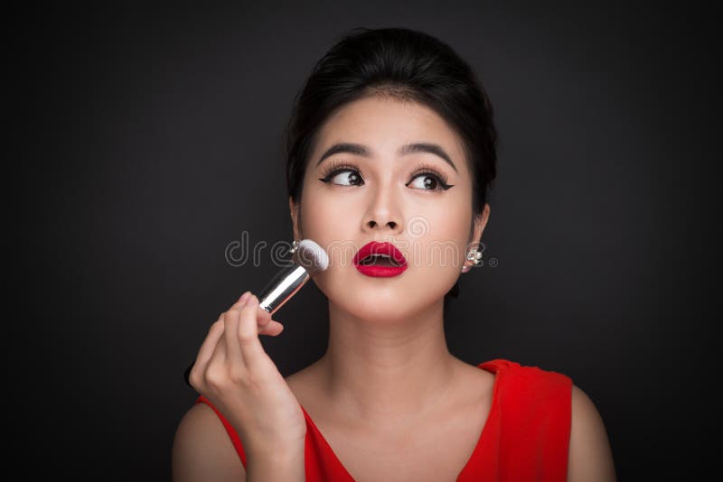 Cosmetic powder brush. Asian woman applying blusher on her cheek