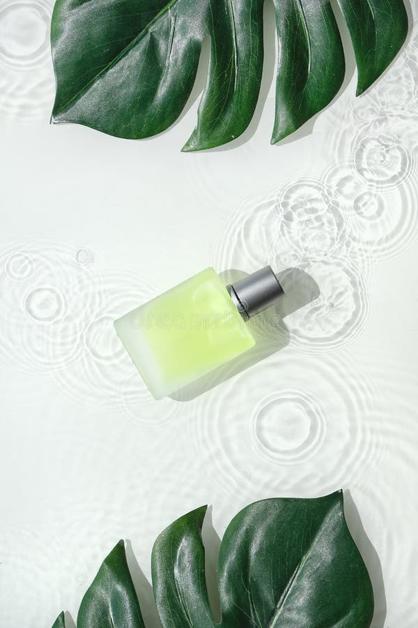 Cosmetic skincare background, splashes of water. Transparent, glass vial with green yellow liquid product and exotic