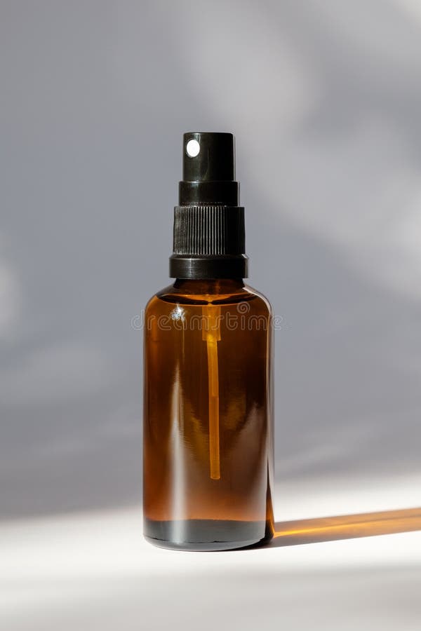 Cosmetische amberkleurige glazen fles met verstuiver op witte achtergrond. ontwerp van natuurlijke organische perfuelverpakkingen