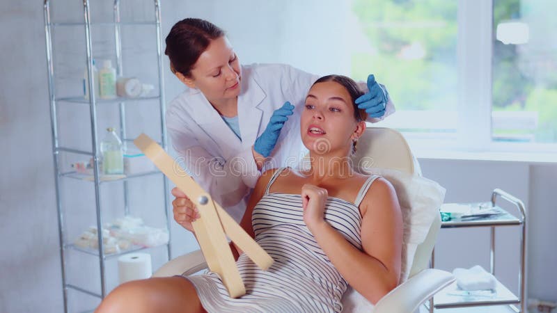 Cosmetologa adulta che esamina la faccia della donna paziente