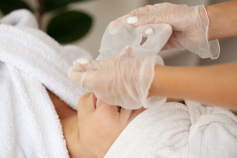 Cosmetologa che applica una maschera per la donna nel salone di bellezza della spa immagini stock