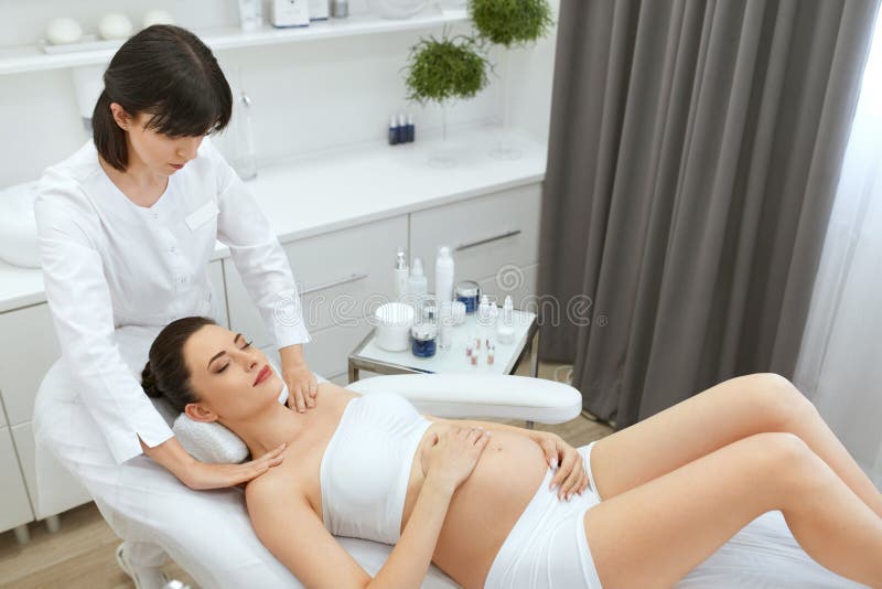 Cosmetologia del fronte Massaggio facciale per la donna incinta alla clinica immagine stock libera da diritti Cosmetologia del fronte Massaggio facciale per la donna incinta alla clinica immagine stock libera da diritti