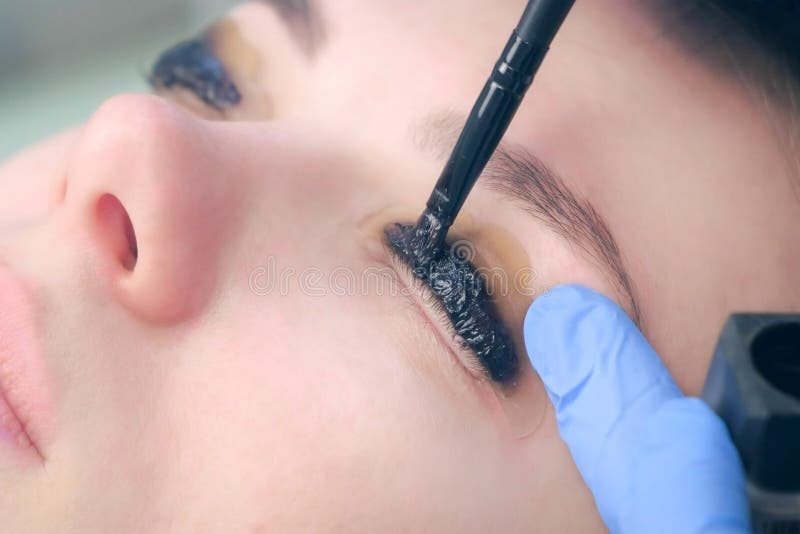 Cosmetologist applying paint for lamination on lashes, lift eyelashes procedure.