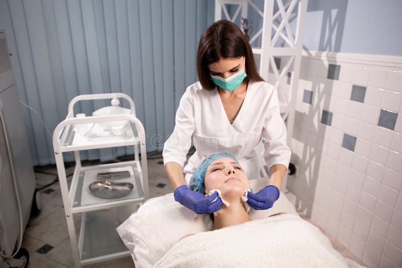 Cosmetologist in blue gloves cleans the patient`s face before cosmetic procedures. Skin health and rejuvenation stock photo Cosmetologist in blue gloves cleans the patient`s face before cosmetic procedures. Skin health and rejuvenation stock photo