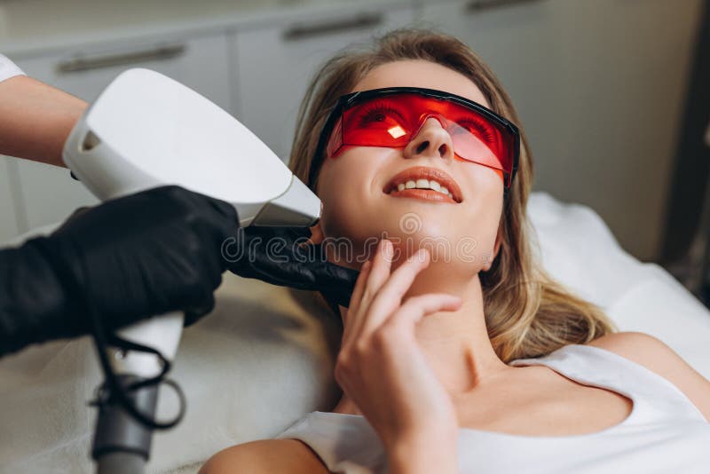 Cosmetologist Doing Laser Epilation To Her Client Adult Woman Lying On Medical Table In Beauty