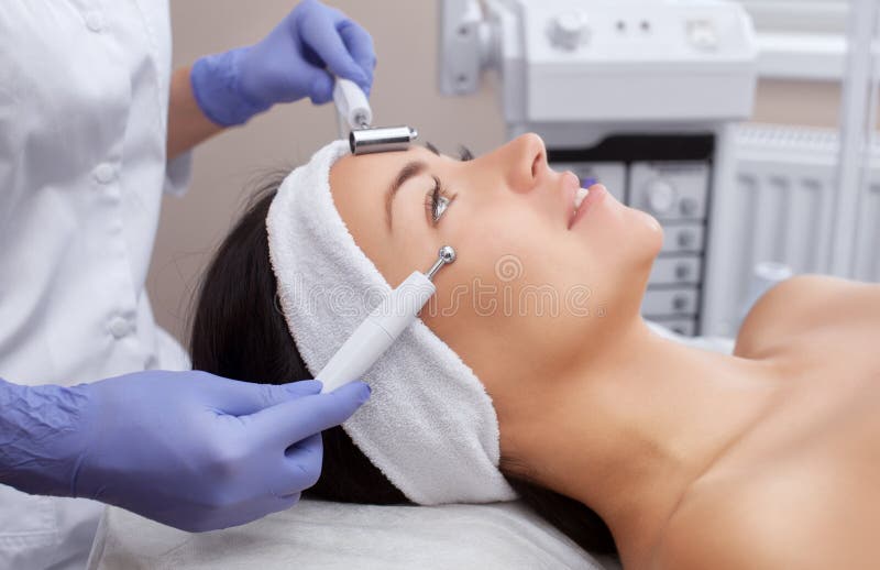 Cosmetologist maakt tot de apparaten een procedure van Microcurrent-therapie van een mooie, jonge vrouw in een schoonheidssalon royalty-vrije stock afbeelding Cosmetologist maakt tot de apparaten een procedure van Microcurrent-therapie van een mooie, jonge vrouw in een schoonheidssalon royalty-vrije stock afbeelding