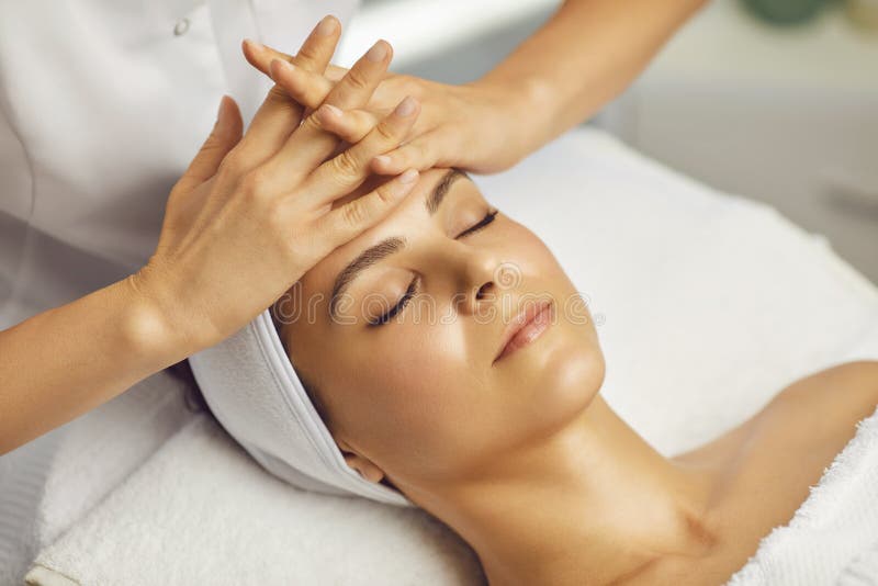 Cosmetologist Making Facial Massage Or Treatment For Young Womans Face In Beauty Spa Salon Stock