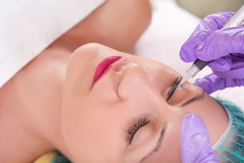 Cosmetologist que aplica maquillaje permanente en ojos fotografía de archivo libre de regalías Cosmetologist que aplica maquillaje permanente en ojos fotografía de archivo libre de regalías